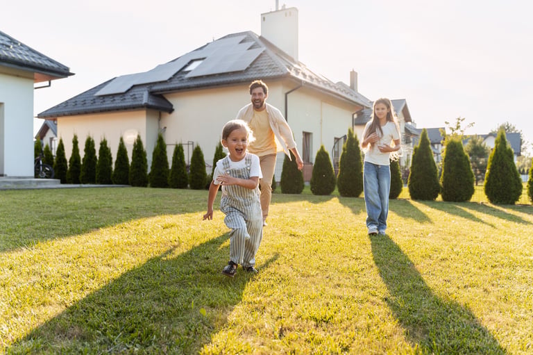 Father and children on the lawn in front of their house with solar panels