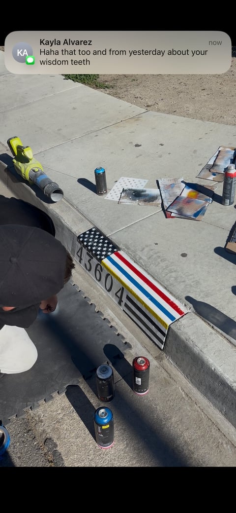 Aerial view of concrete curb with spray paint cans and stencils including a patriotic American flag design and address numbers