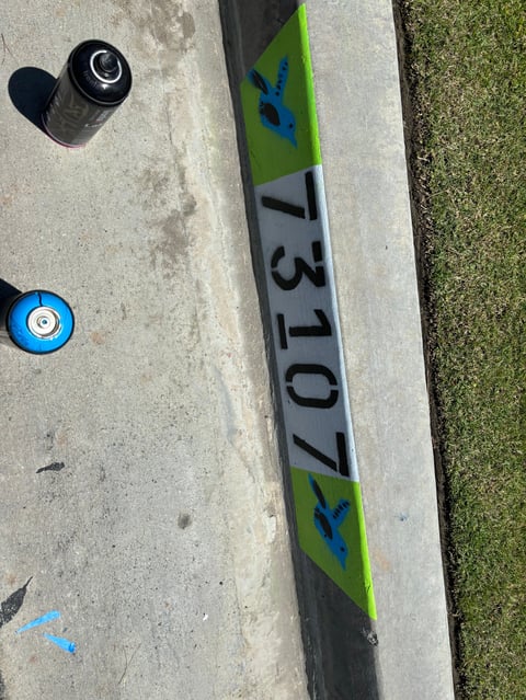 Windsurfing boom with green and black color scheme displaying model number 1370, placed on concrete with two round weights nearby