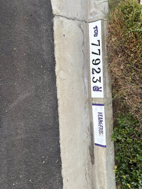 Concrete curb with white label showing number 1625 and BARKING text next to asphalt road and grass