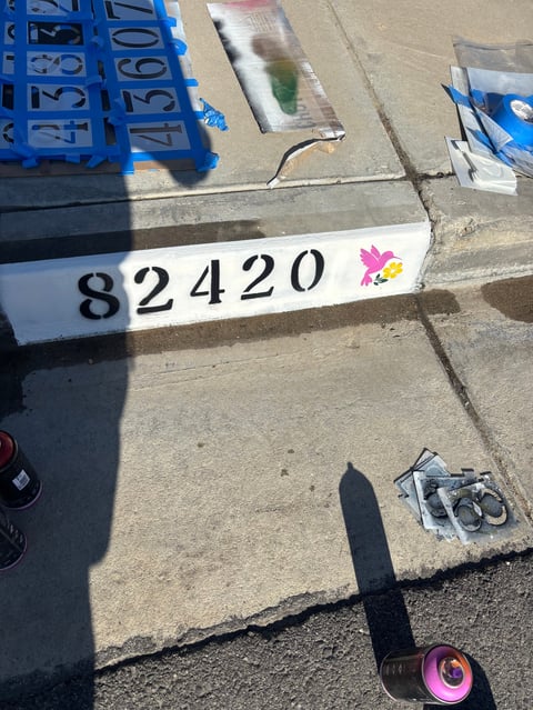 White label with number 82420 and pink flower icon on concrete surface surrounded by blue crates and equipment