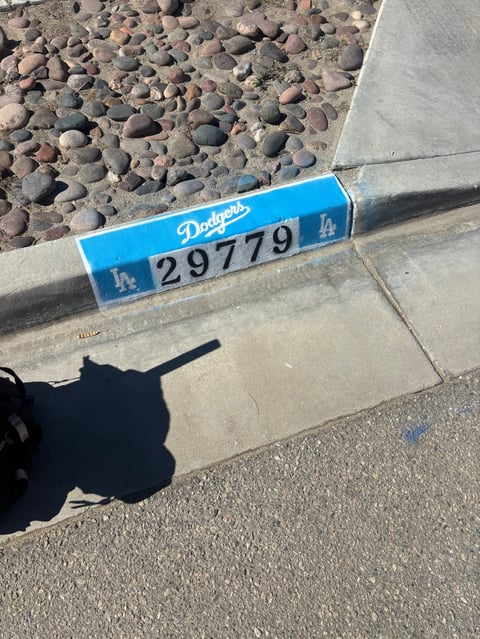 Blue Los Angeles Dodgers parking permit 29779 placed on concrete with rocky ground and photographers shadow visible