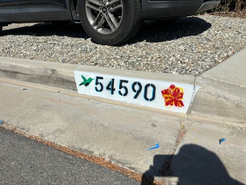 White parking space marker with blue arrow, number 54590, and red maple leaf symbol on concrete