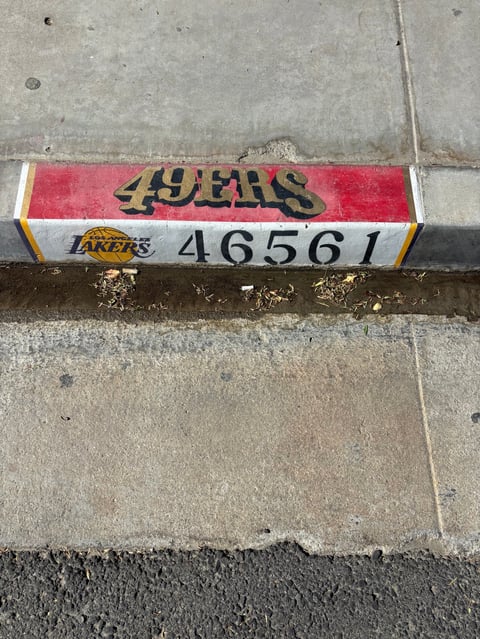 NBA team merchandise bar with 49ers and Lakers logos and number 46561 on concrete surface
