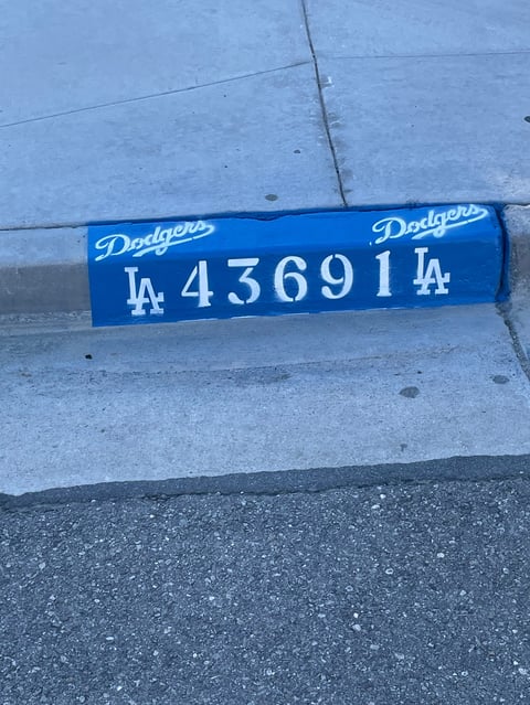Blue Los Angeles Dodgers license plate displaying LA 436914 mounted on gray concrete surface