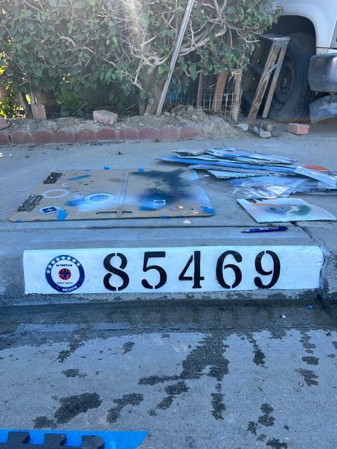 Evidence display with numbered identification marker 85469 showing seized blue materials and items laid out on pavement