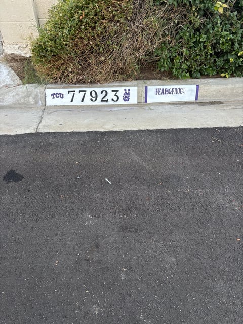 Parking lot curb with white address marker showing number 77923 and HEADI.FROC text label