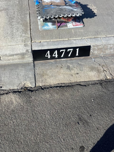 Overhead view of concrete pavement with black scale marker labeled 44771 and evidence collection kit on cracked asphalt