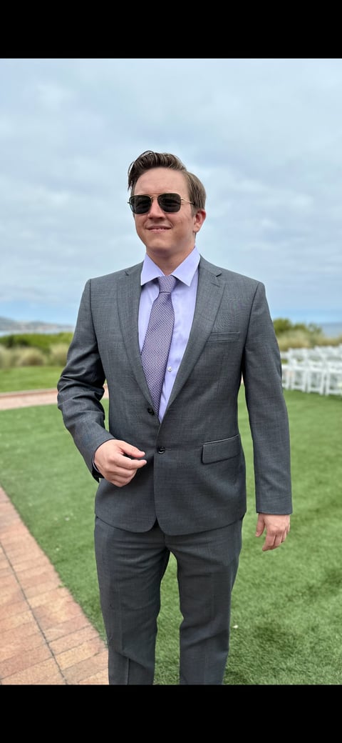 Taylor Nowlan, Co-Founder of Curb2Current, in gray suit and sunglasses on outdoor lawn
