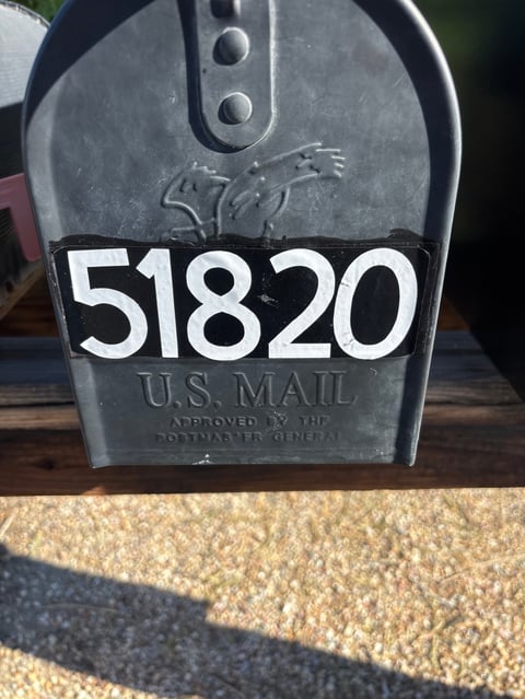 Black U.S. Mail mailbox with address numbers 51820 displayed on metal plaque