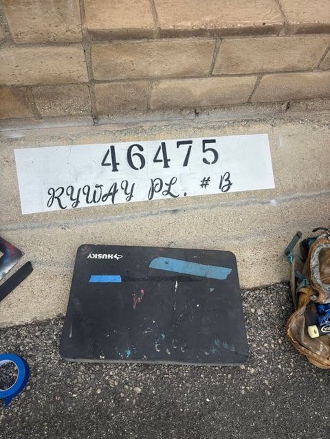 Black laptop with blue tape on concrete surface next to white inventory label reading 46475