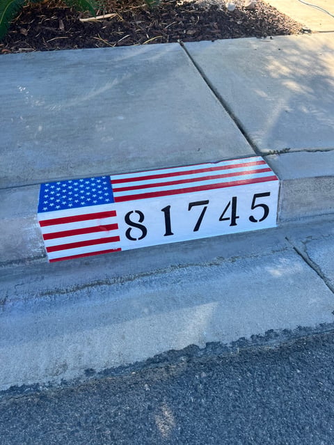 American flag labeled scale marker displaying number 81745 placed on concrete pavement