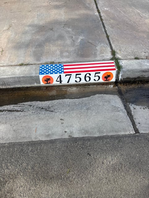 American flag ruler with number 47565 and orange markers on cracked concrete pavement
