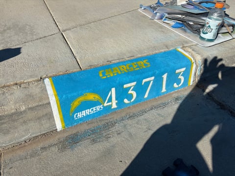 Blue Chargers NFL foam finger with number 43713 on concrete surface with shadow of person visible